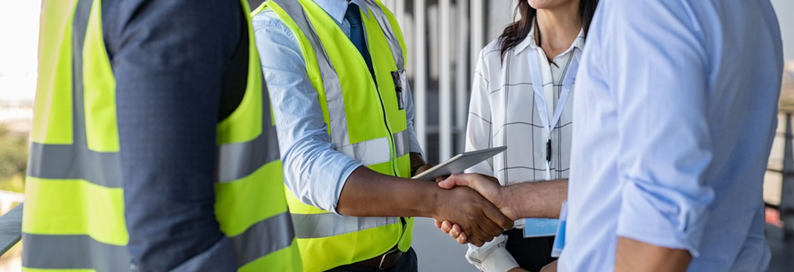 A man in construction uniform shakes hand with business man